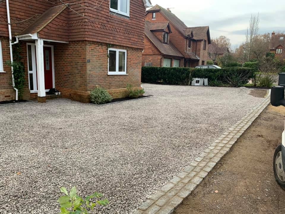 A finished gravel driveway with a block-paved edge in front of brick houses
