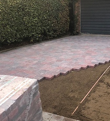 Red brindle block paving laid in a herringbone pattern up to a garage