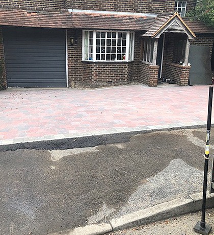 A finished block-paved drive in front of a house with a porch and garage