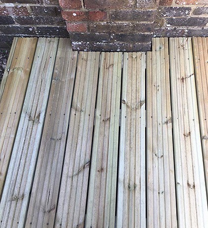 Close view of new deck boards meeting a brick wall