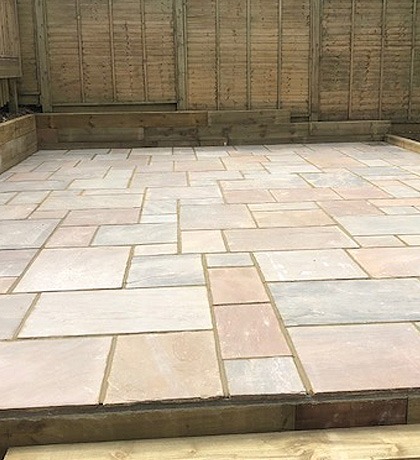 The finished sandstone patio inside its timber frame against the fence