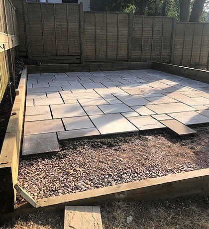 Sandstone slabs going down on a prepared base inside a timber edge