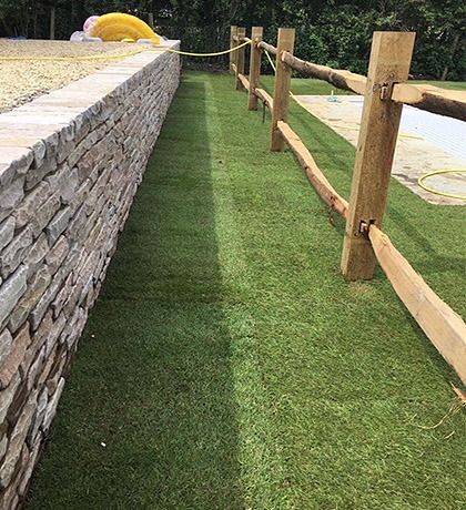 Post and rail fencing beside a dry stone wall and new turf