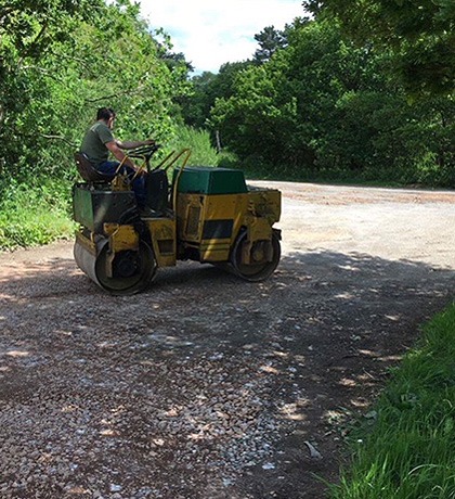 A ride-on roller compacting a new base