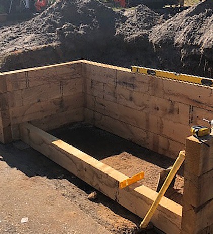 Oak sleepers being set into a dug-out bank, with a spirit level on top