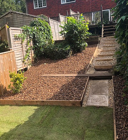 A sloping garden with a stepped sleeper path and gravelled beds