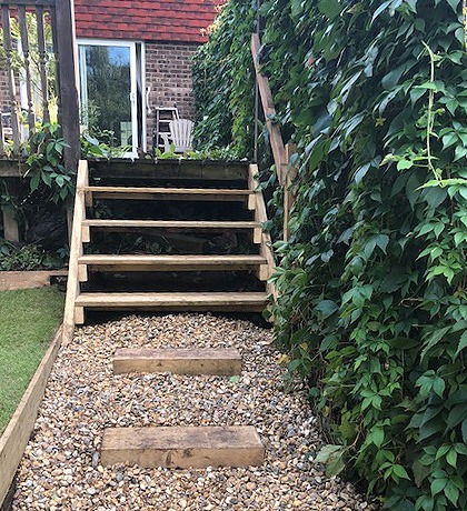 Sleeper steps rising through a gravel path between climbing plants
