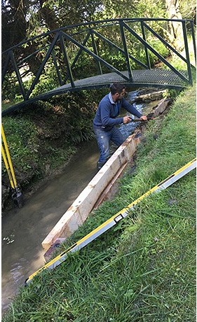 One of the team standing in a stream fixing sleepers along the bank