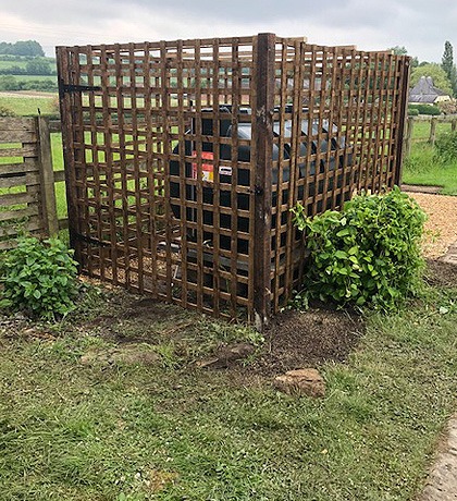 A timber trellis screen hiding bins at the side of a drive
