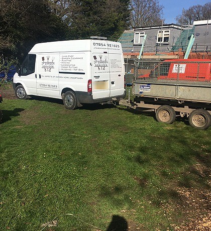 The white JF Garden Services van, with its livery, towing a caged trailer
